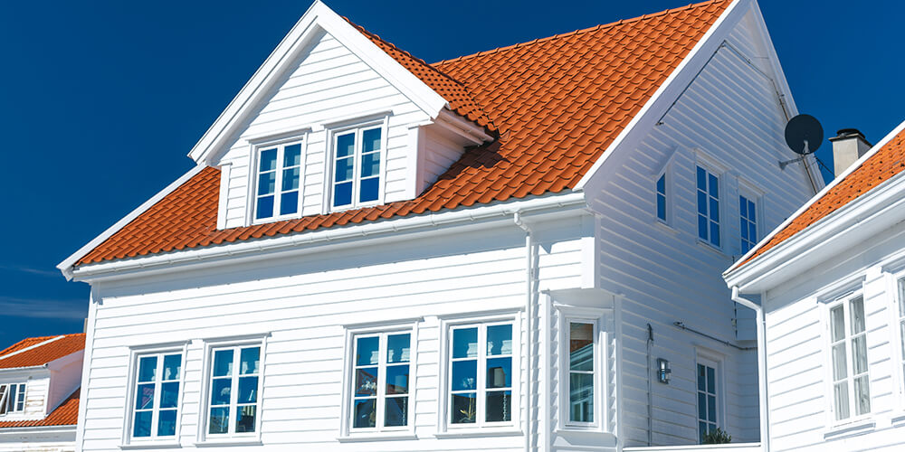 Bild av ett vitt hus med fönster utrustade med mittposter och spröjs.