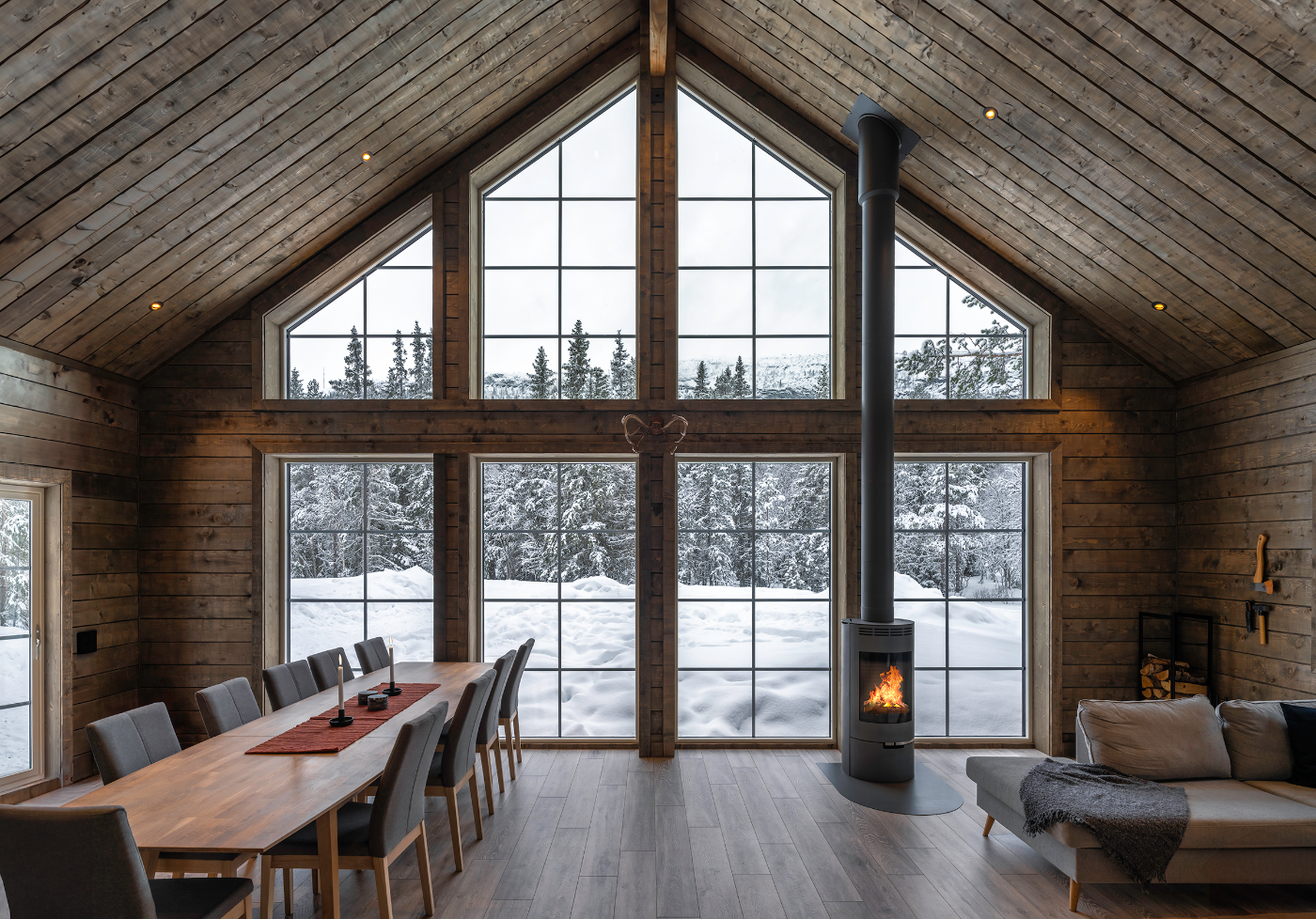 Store sprossevinduer i en tømmerhytte med utsikt mot snødekt skog. Sprossene gir vinduene et klassisk og tidløst uttrykk.